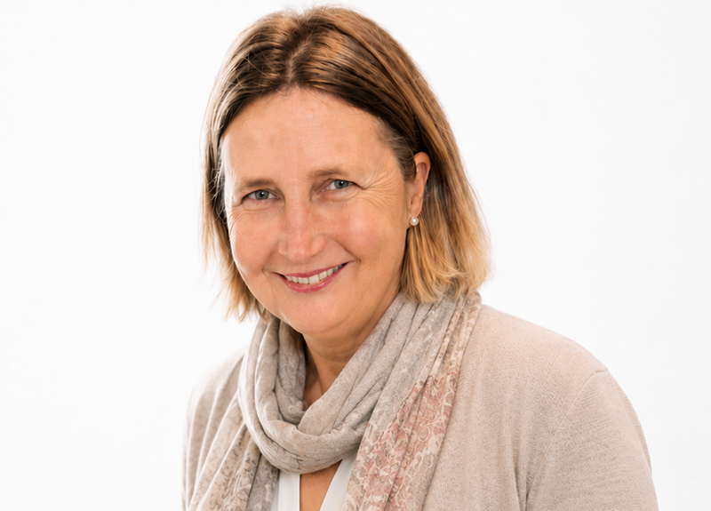 Smiling woman in a light beige sweater and scarf against a white background