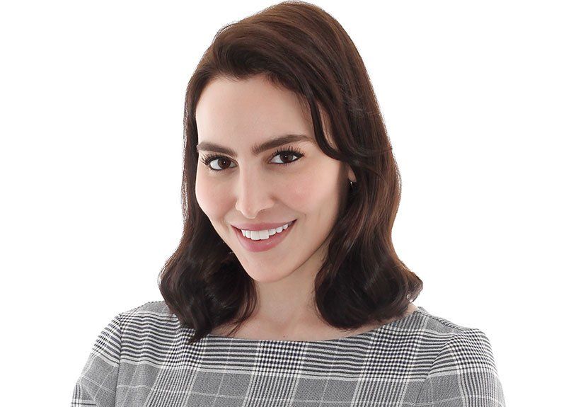 a woman in a plaid shirt smiles for the camera