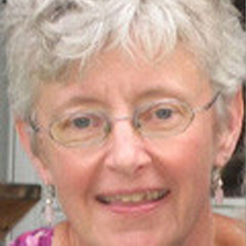 A close up of a woman wearing glasses and smiling.