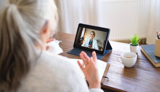 Person video chatting on a tablet at a wooden table with a coffee cup and small plant.