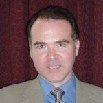 A man in a suit and tie is smiling for the camera.