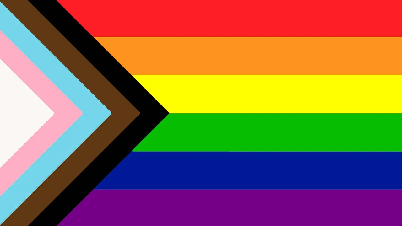 A close up of a rainbow flag with an arrow pointing to the right.