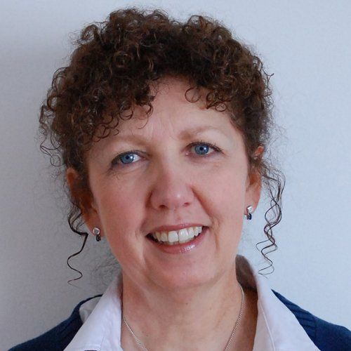A woman with curly hair is smiling for the camera