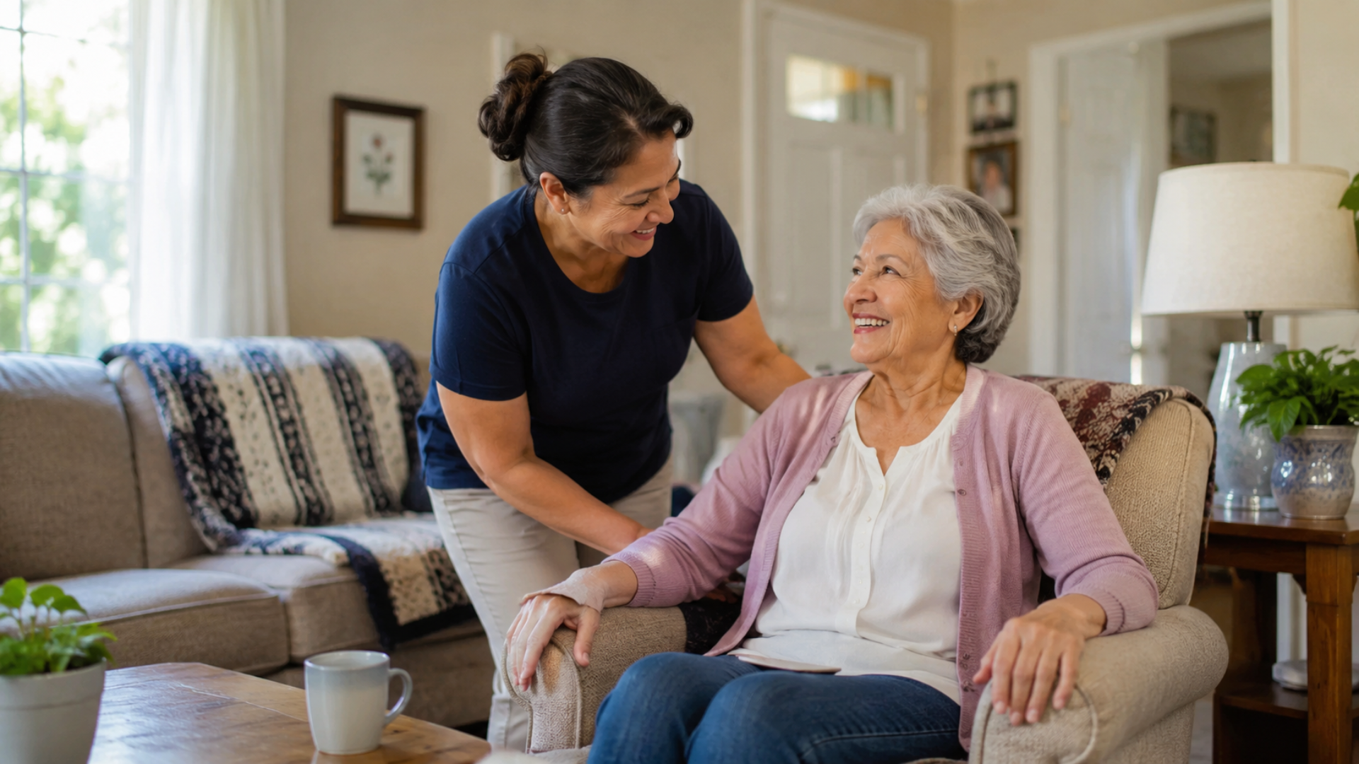 Caregiver consoling an elderly woman on a couch in a bright living room