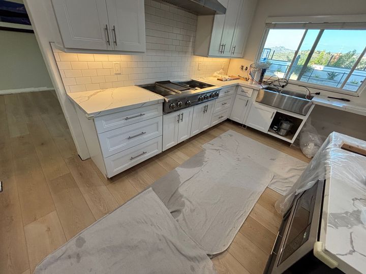Modern kitchen with white cabinets, gas range, light wood floors, and a rug on the floor