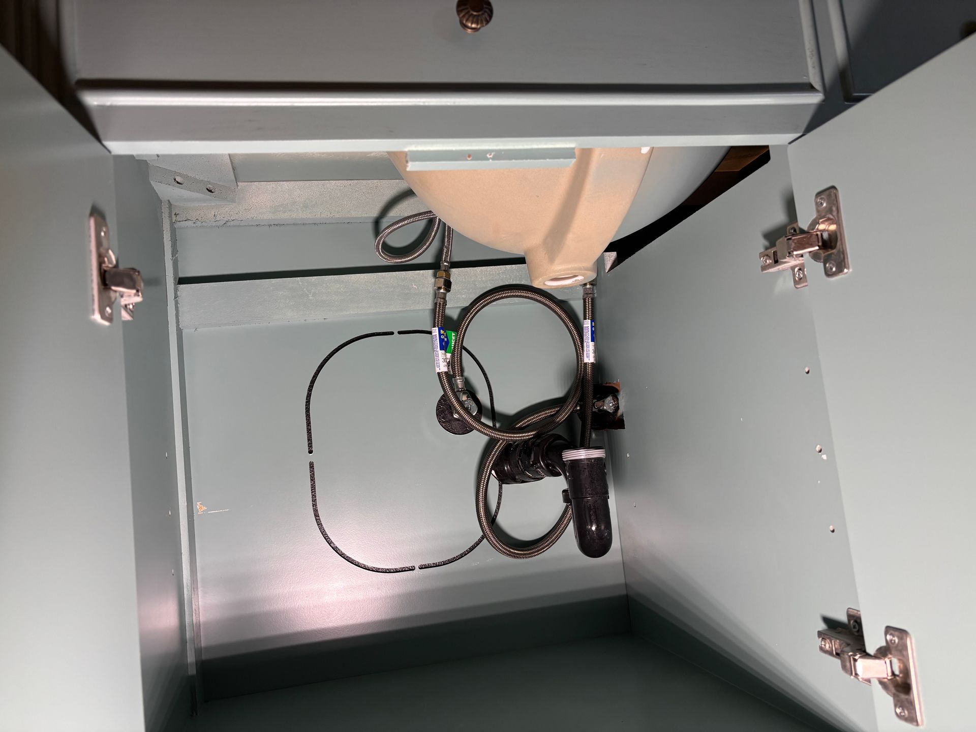 Open cabinet with tangled cables and a small black device inside.