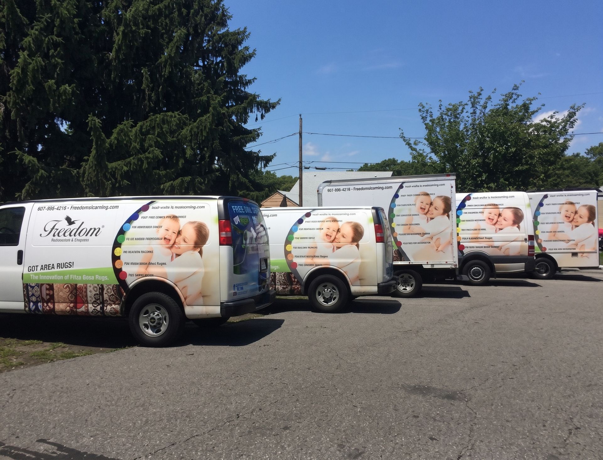 Fleet of white delivery vans with fruit graphics parked in a lot on a sunny day