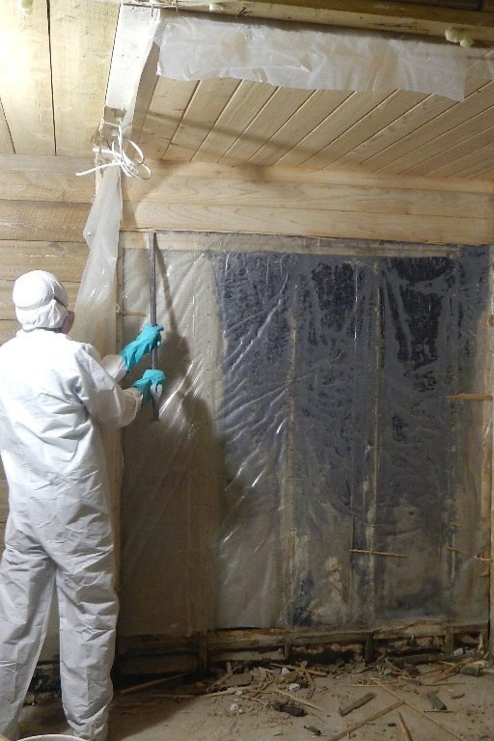 Worker in white protective suit spraying foam insulation on a wall inside a building under construction