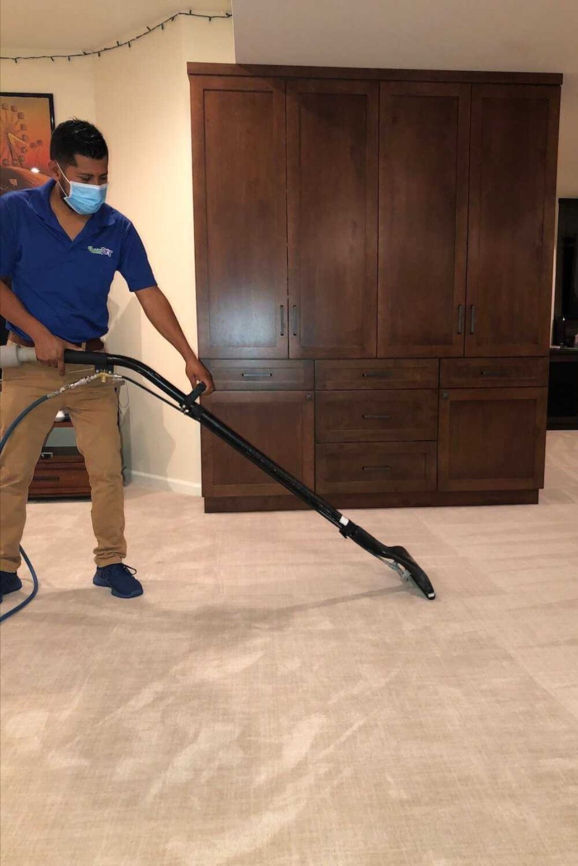 Person vacuuming a marble floor in a room with a large wooden cabinet