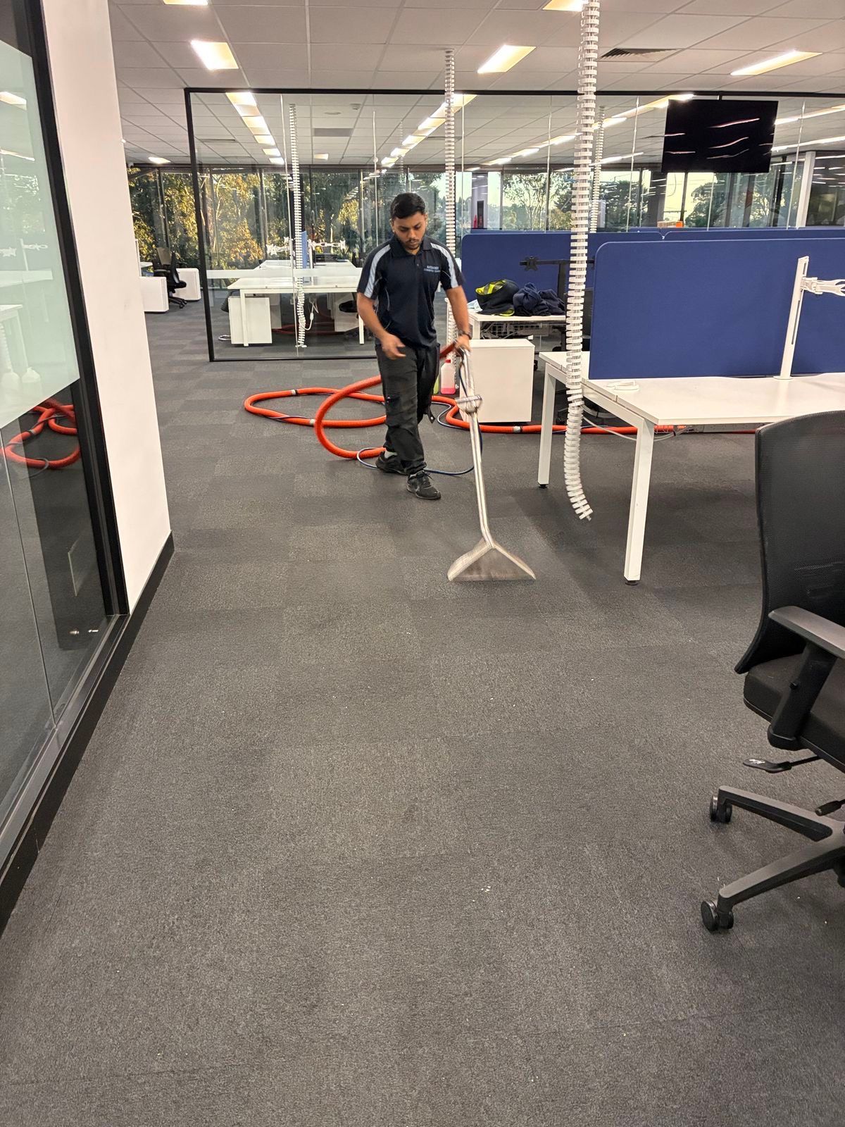 Person standing in an office hallway near red cables, desks, and white partition panels