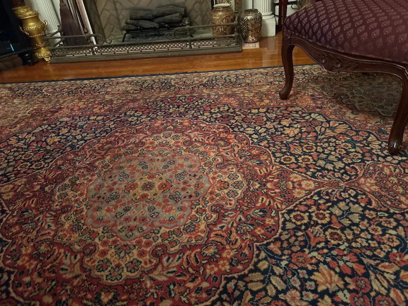 Patterned red and blue oriental rug in a living room with a fireplace and chair