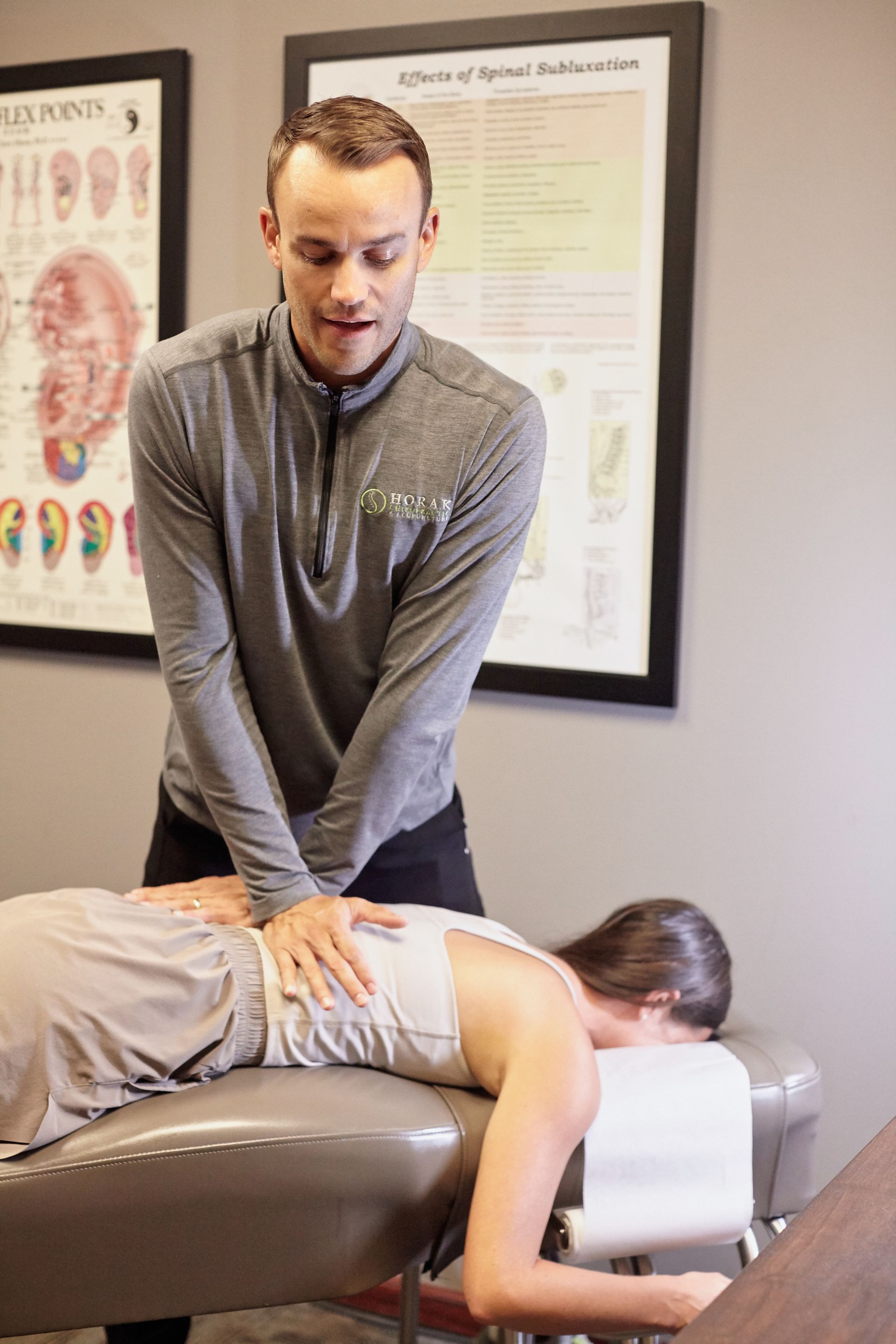 Chiropractor adjusting a patient lying face down on a treatment table in a clinic.