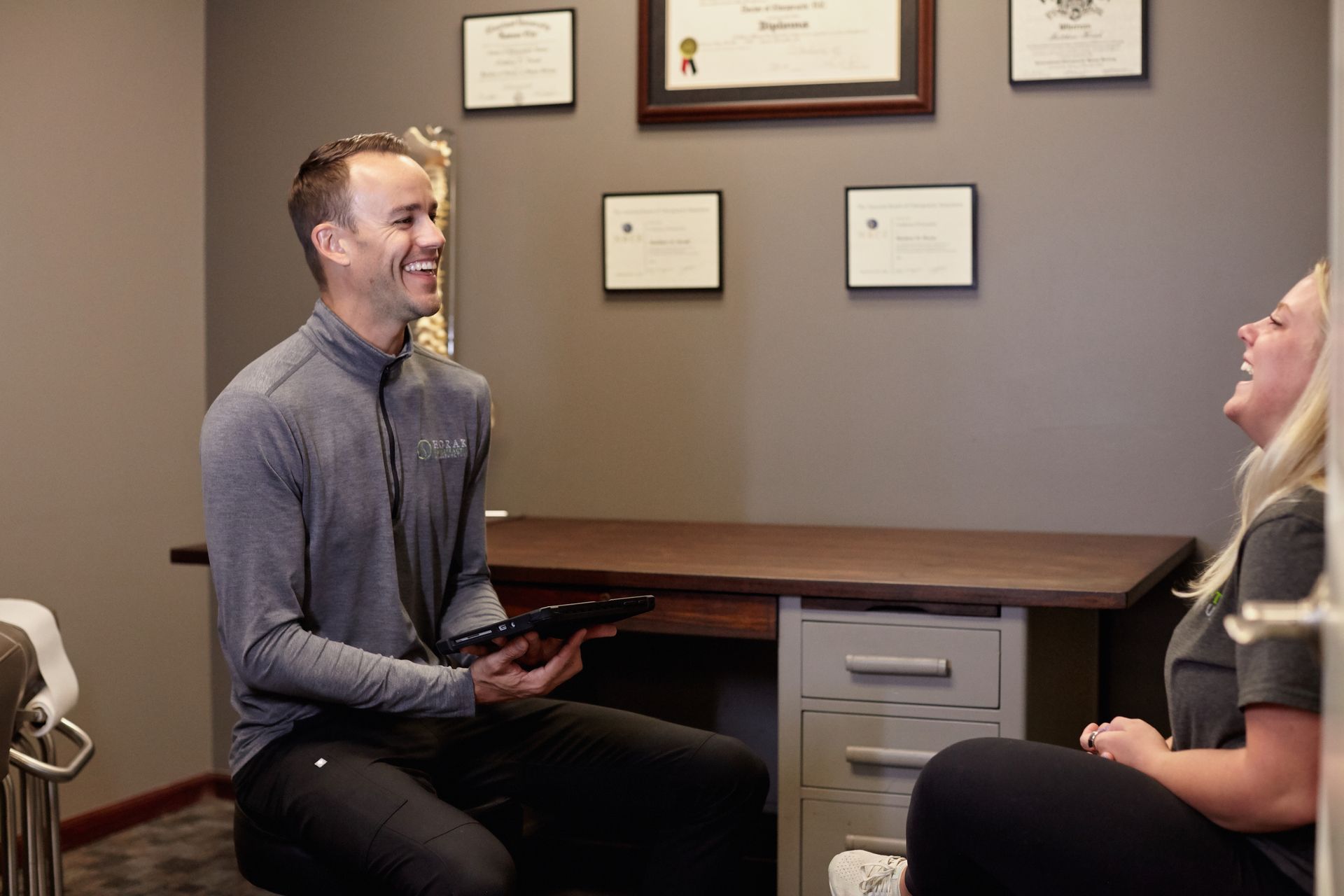 Two people seated facing each other in a small office, smiling during a conversation.