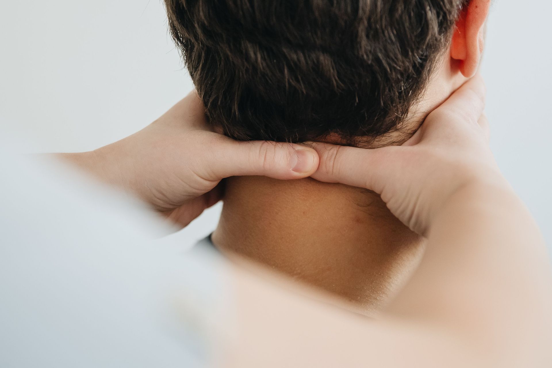 Hands pressing the back of a person's neck in a close-up massage scene