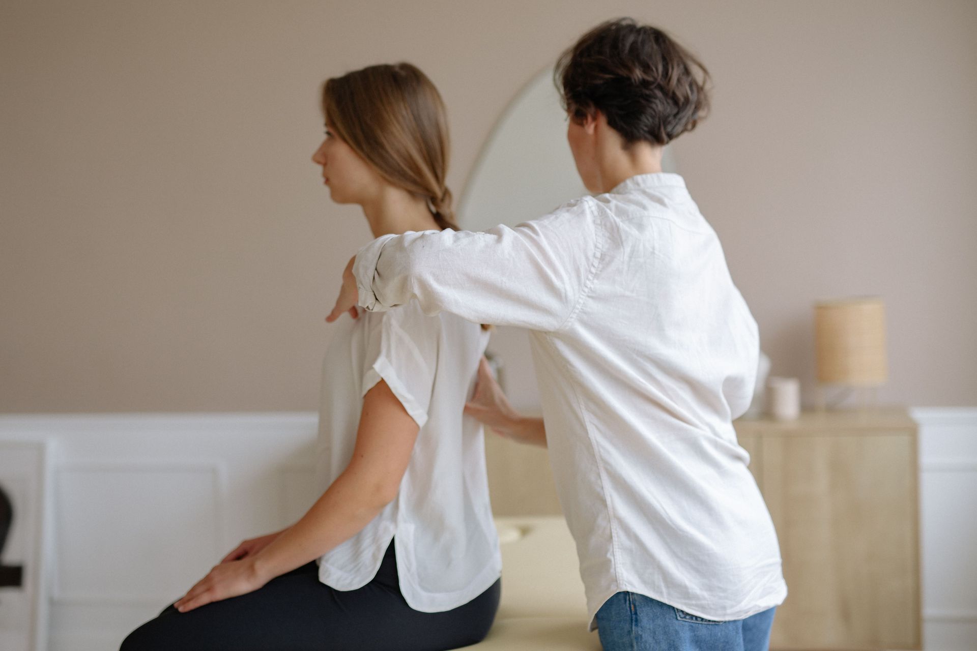 Person receiving a shoulder massage from a therapist in a bright room