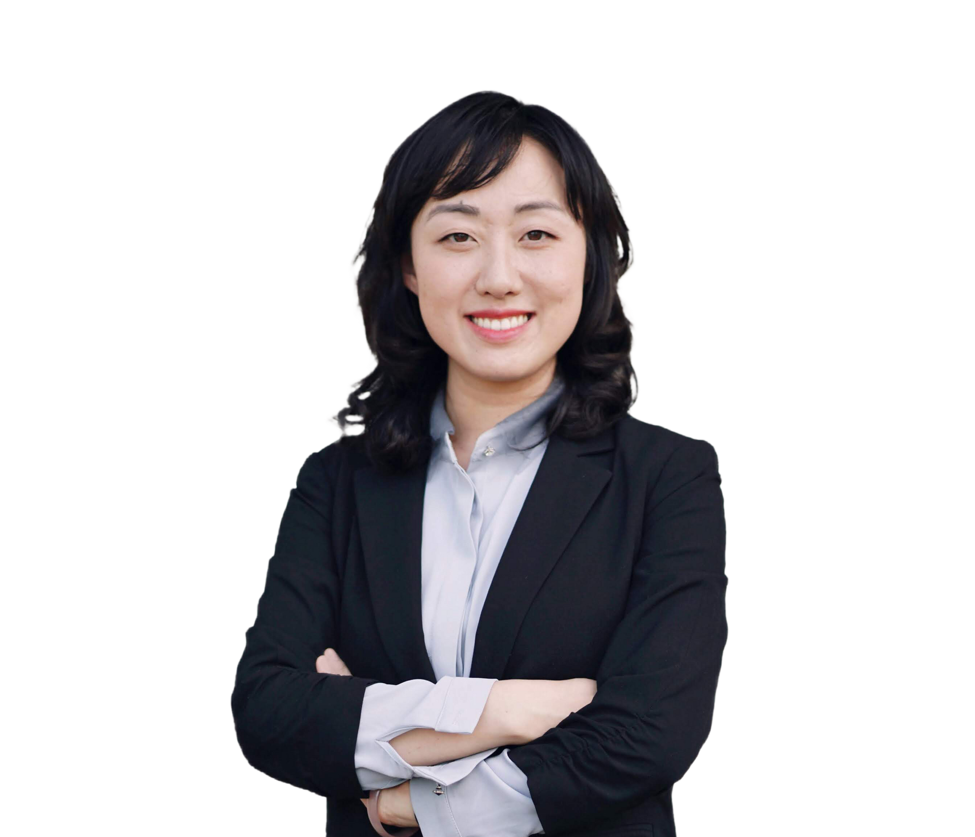 A woman in a suit is standing with her arms crossed and smiling.