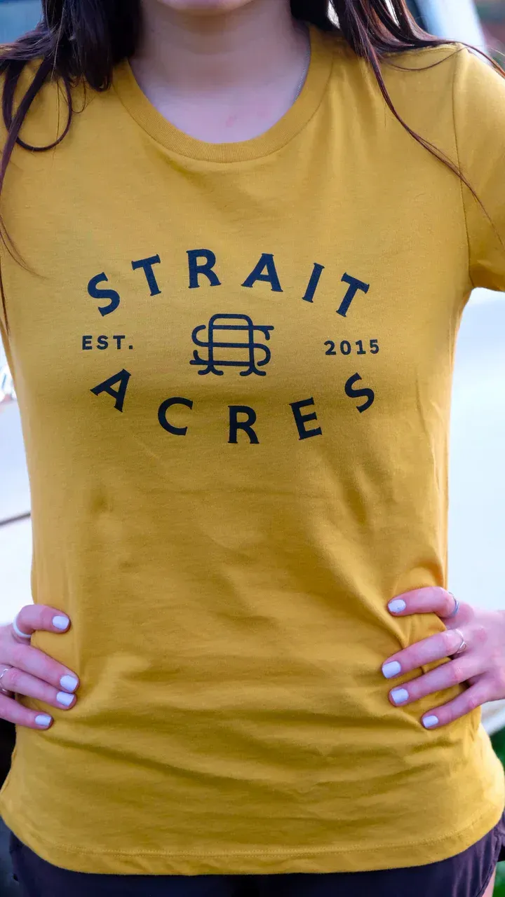 Woman wearing a mustard-colored t-shirt with the text