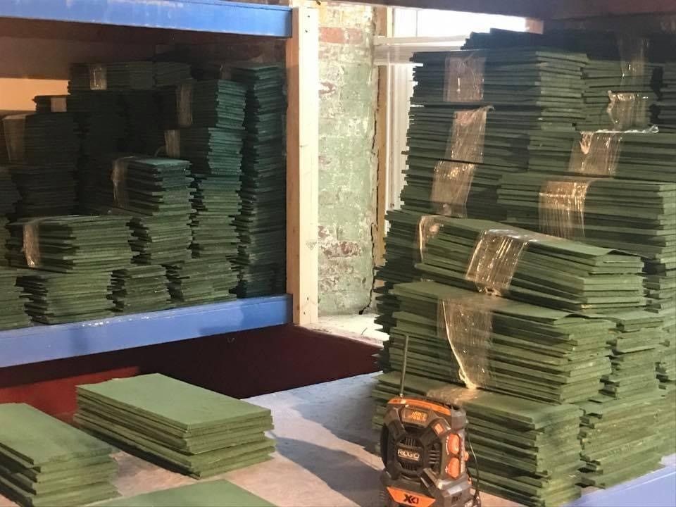 Stacks of green bills piled in a safe or storage compartment, with a money counting machine in front.