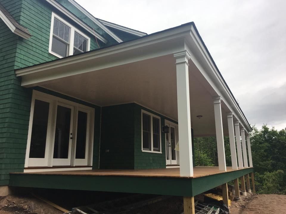 Green house with white trim and a covered porch supported by white columns