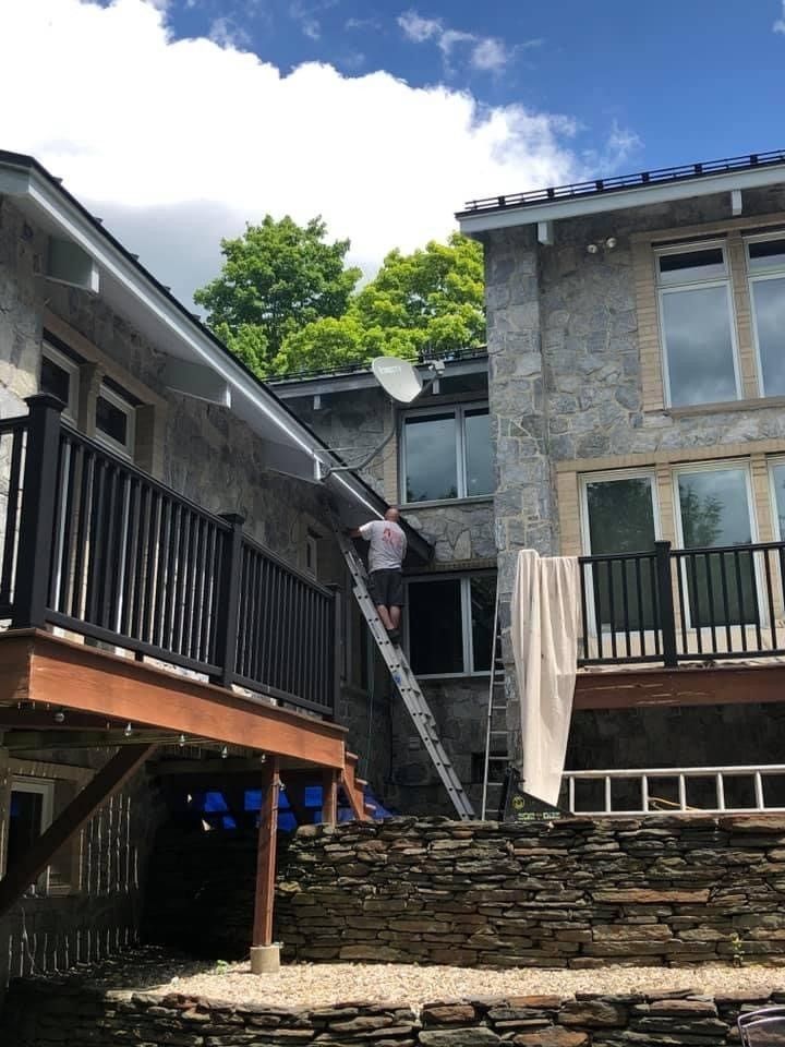 Stone buildings with a wooden balcony, outdoor stairs, and a draped towel in a courtyard.