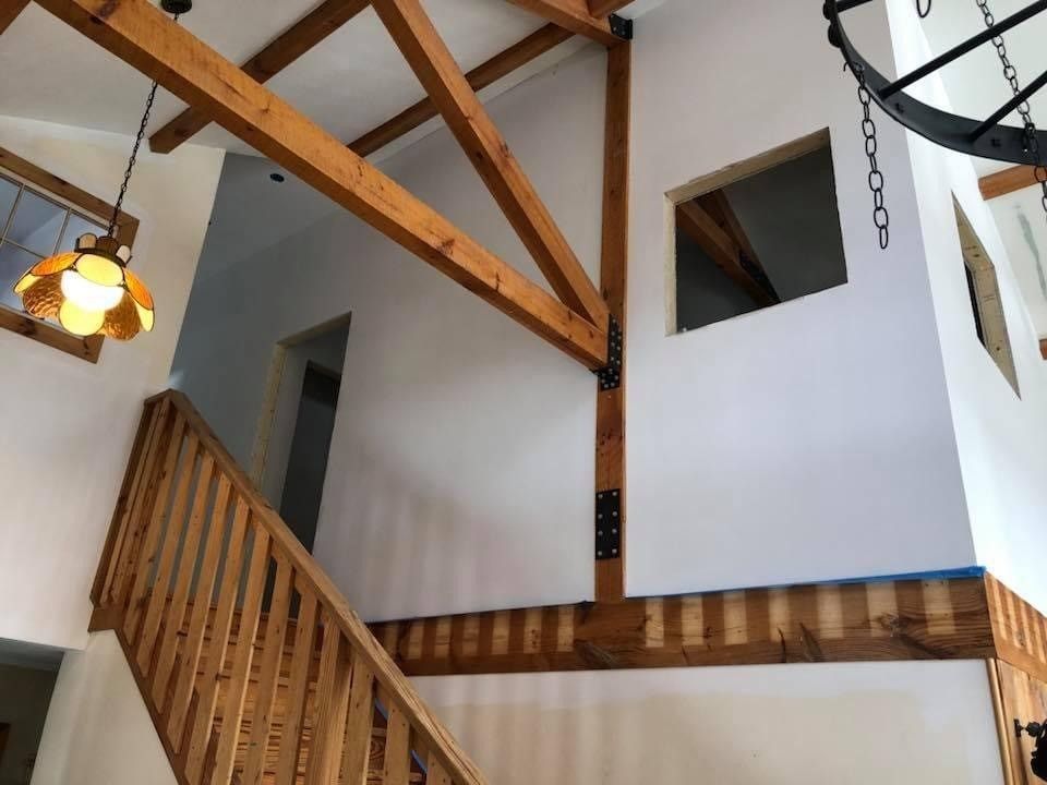 Interior with wooden beams, staircase, and white walls in a bright entryway