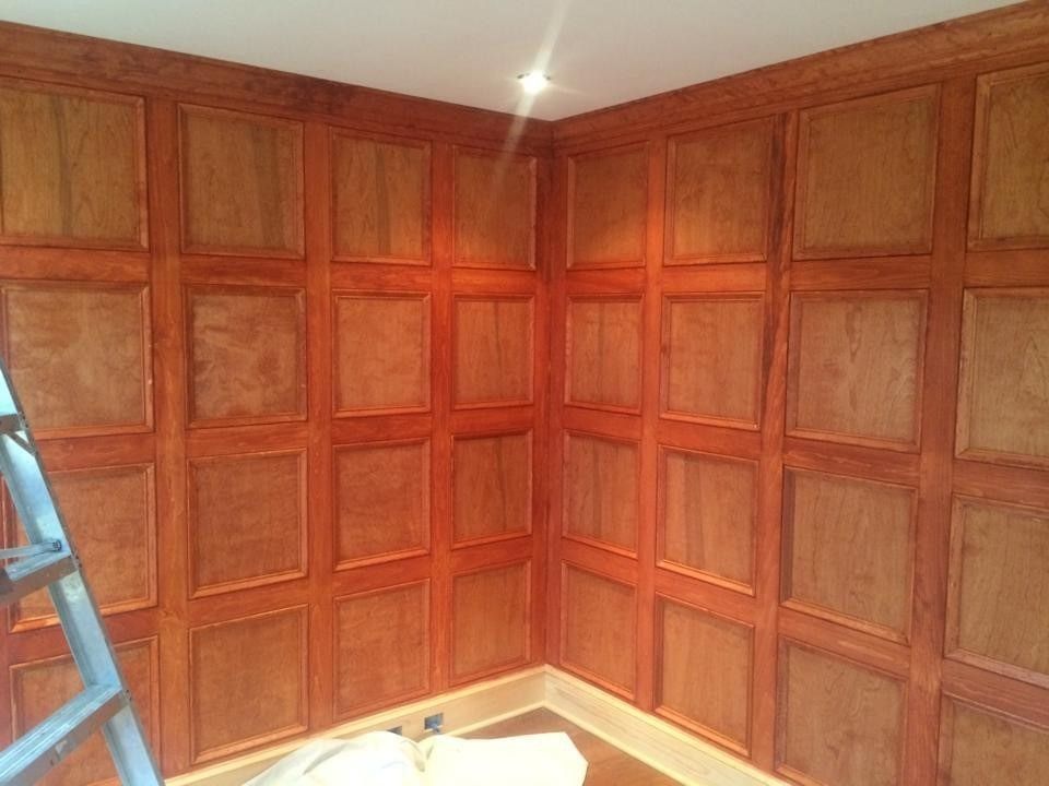 Wood-paneled corner room with a ladder on the left and a bright ceiling light above