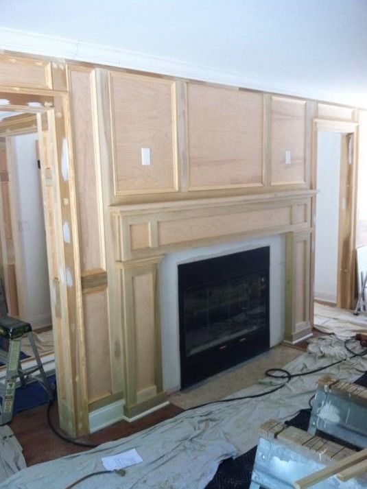 Unfinished wood fireplace mantel and built-in wall paneling in a room under construction