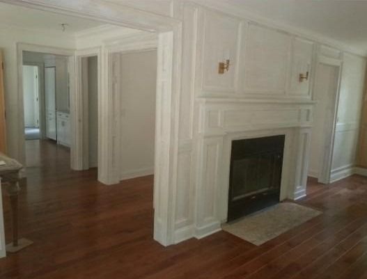 Bright living room with hardwood floors and a white fireplace mantel