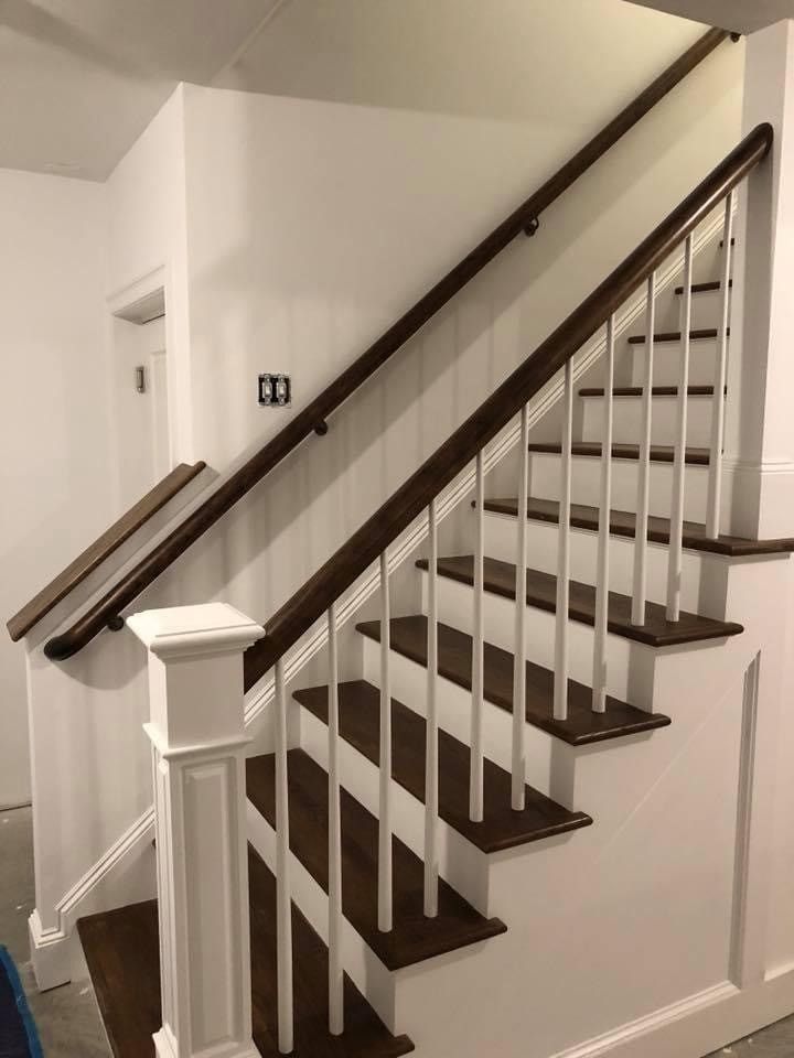 Interior staircase with dark wood steps, white balusters, and a brown handrail against white walls