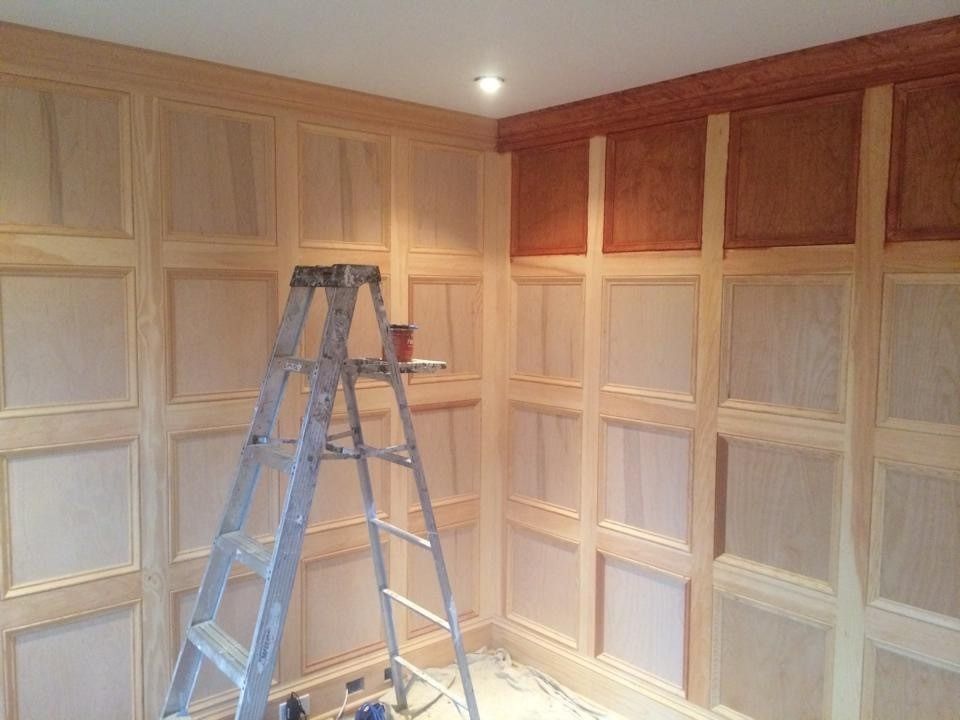 Ladder in a room with unfinished wood paneling and cabinets, lit by a ceiling light.