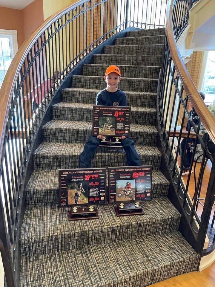 Child seated on carpeted stairs with a boxed toy set, surrounded by more toy boxes on the steps