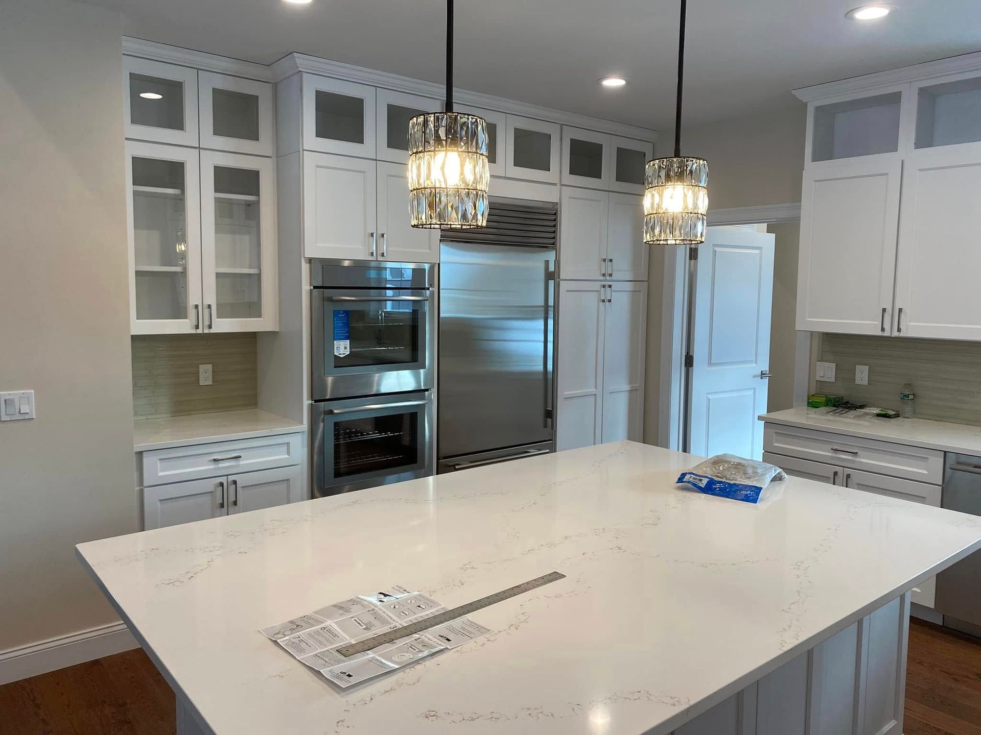 Bright modern kitchen with white cabinets, large island, stainless steel appliances, and pendant light