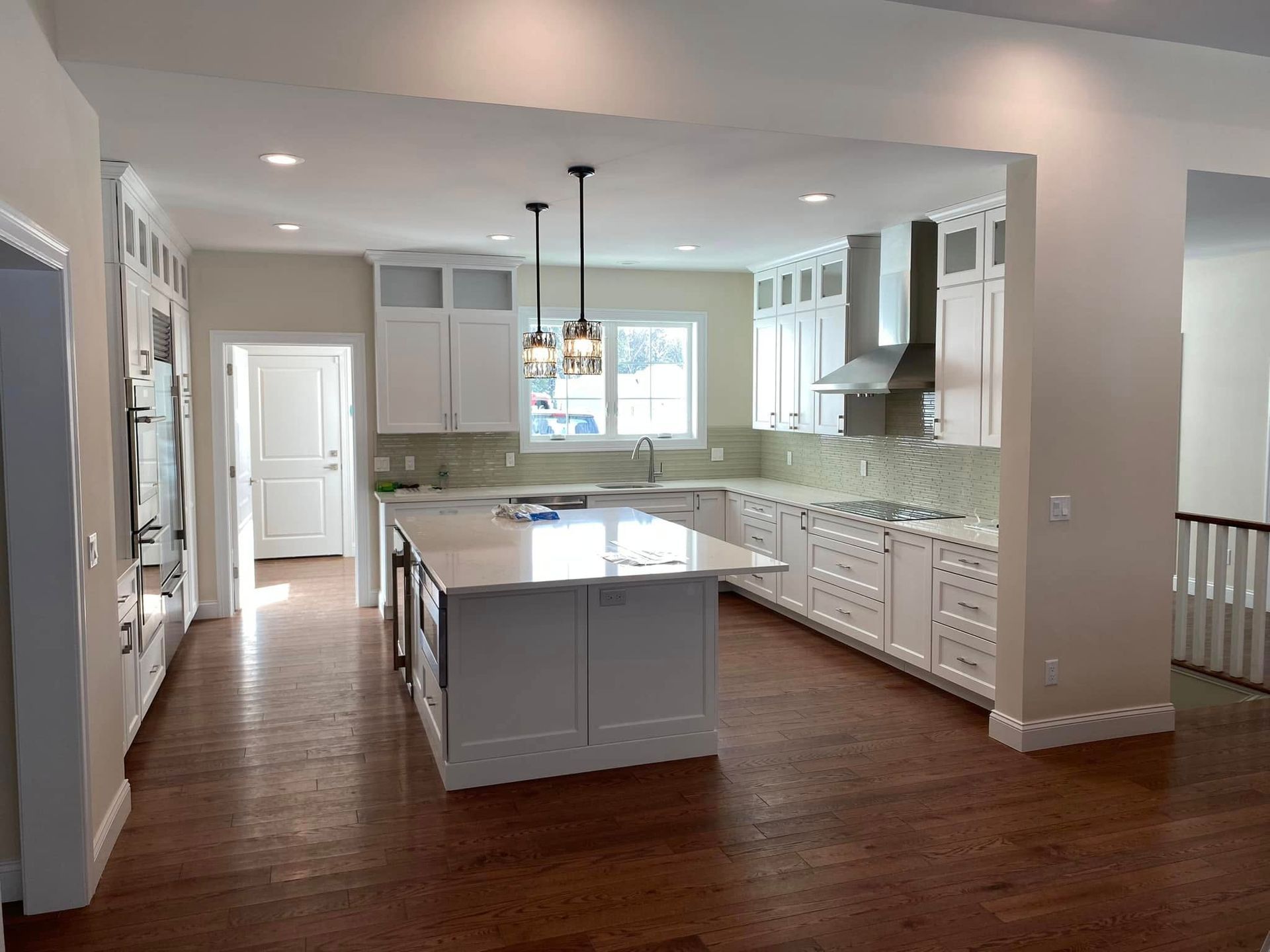 Bright modern kitchen with white cabinets, gray island, wood floor, and large window