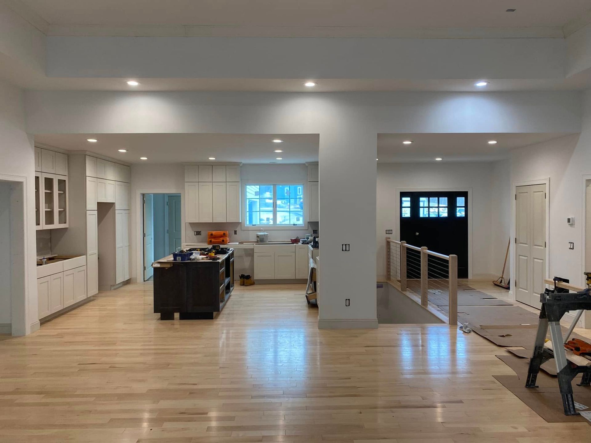 Bright, open kitchen and living area with light wood floors, white cabinets, and island under recessed lighting