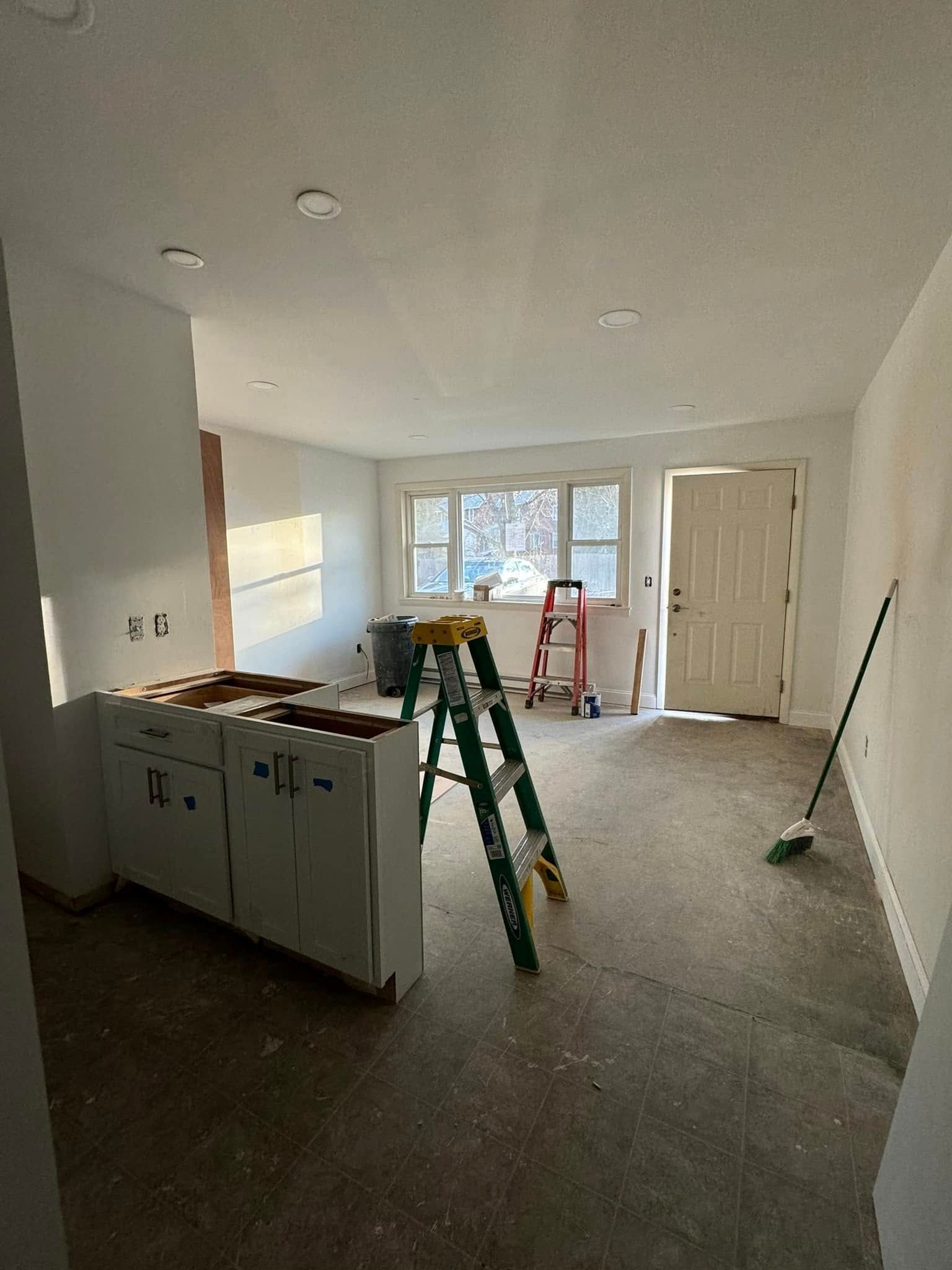 Renovated living room with ladders, tools, and unfinished cabinets in progress
