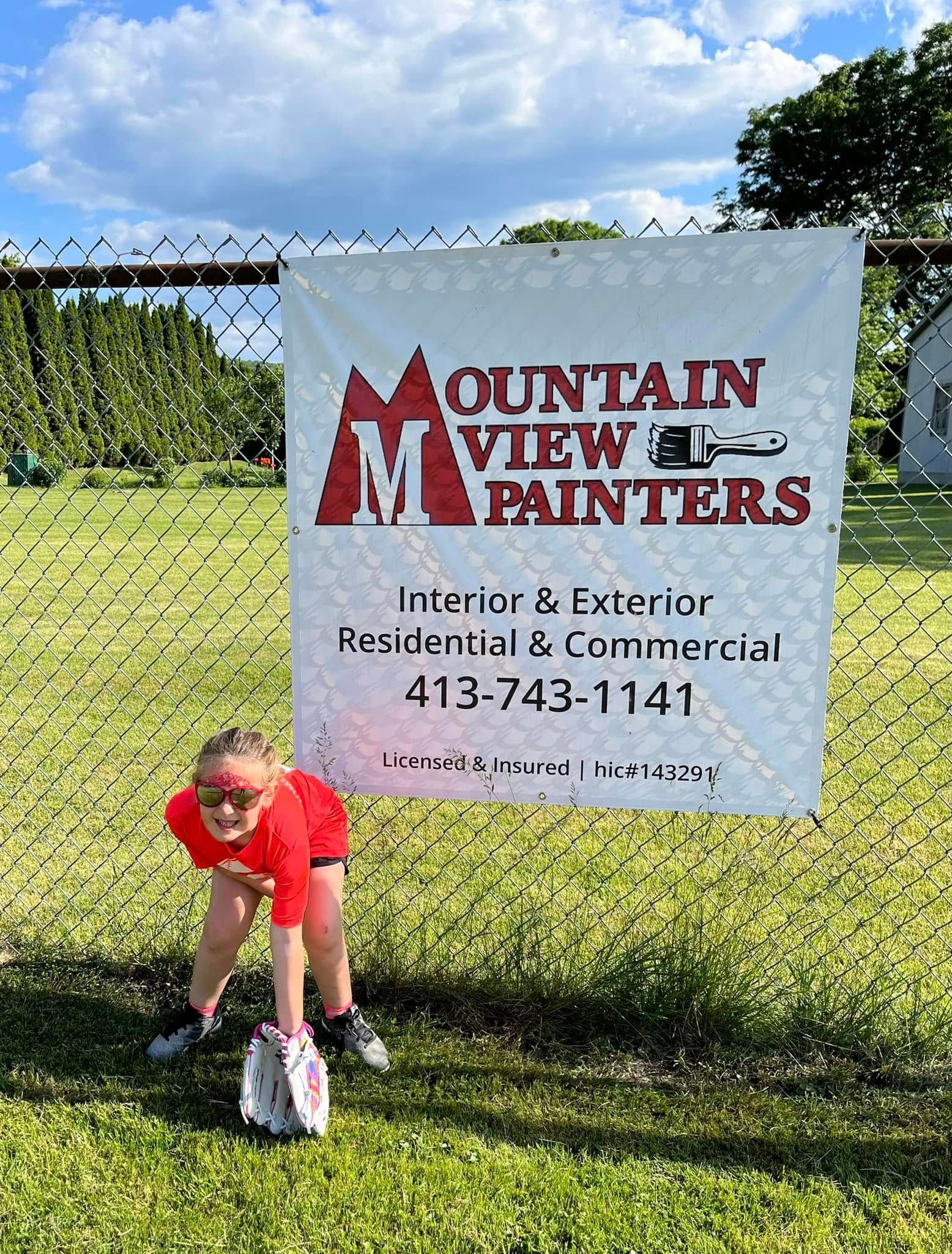 Child in red bending by a fence banner reading “Mountain View Painters” with a phone number.