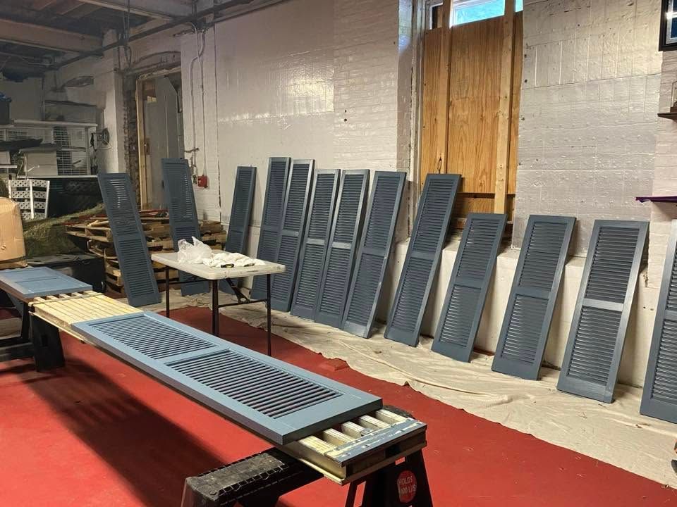 Factory workshop with metal slat conveyor parts and blue vent panels leaning against a wall