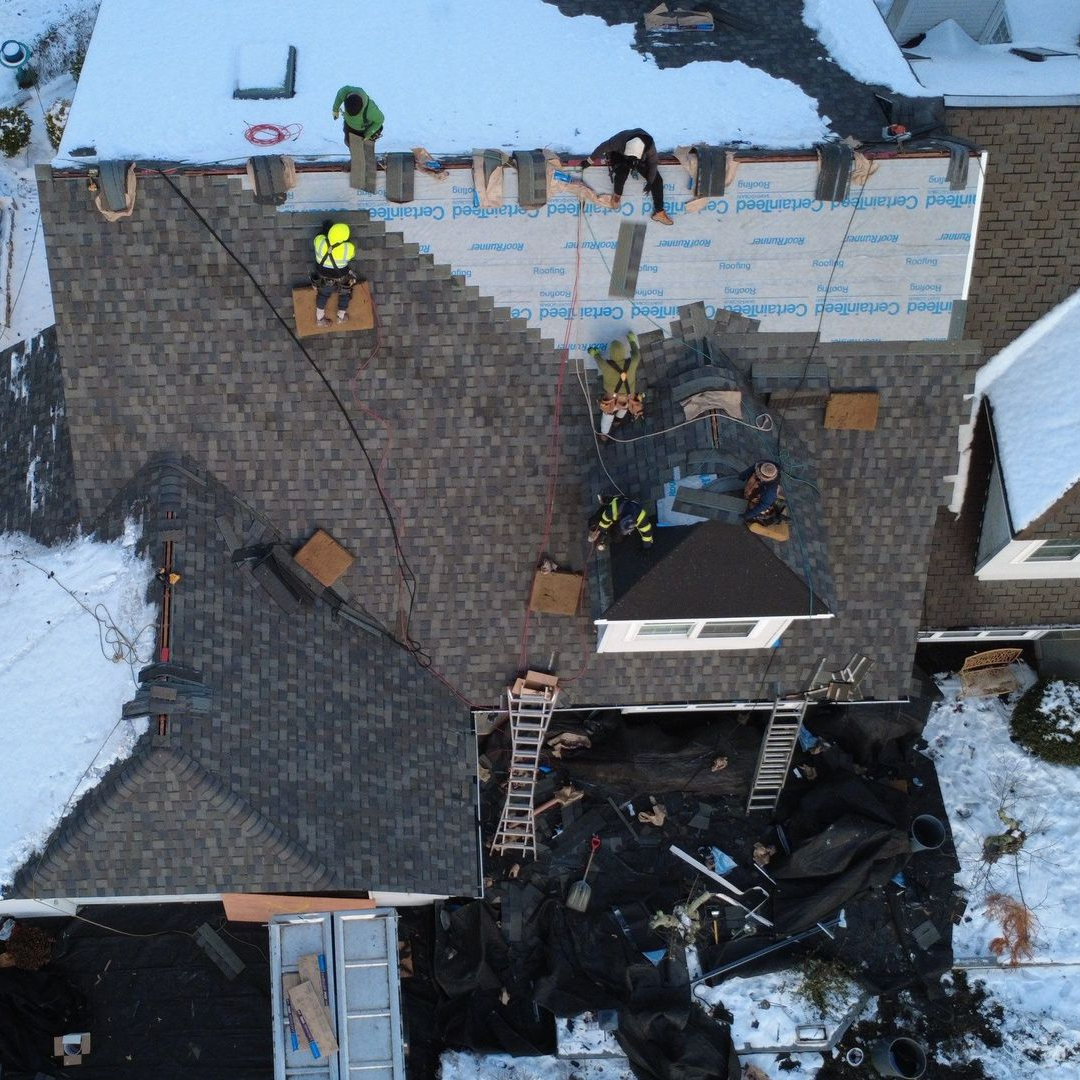 A person is holding a hammer in front of a roof A person is holding a hammer in front of a roof