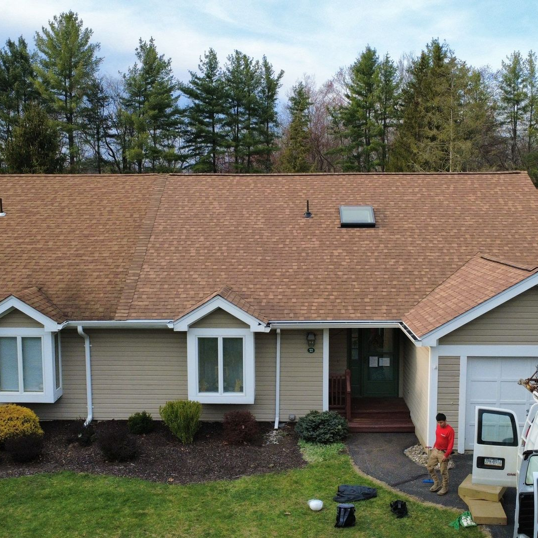 Aerial view of a house under construction with a gray shingle roof and green sheathing. Aerial view of a house under construction with a gray shingle roof and green sheathing.