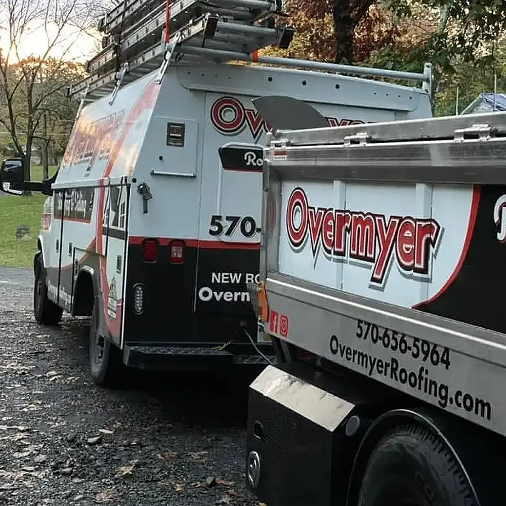 Two overmyer roofing trucks are parked next to each other