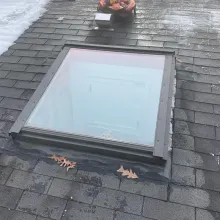 A skylight is sitting on top of a brick roof.