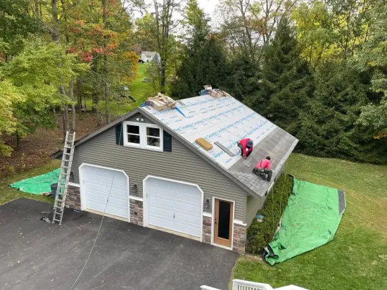 A couple of men are working on the roof of a garage.