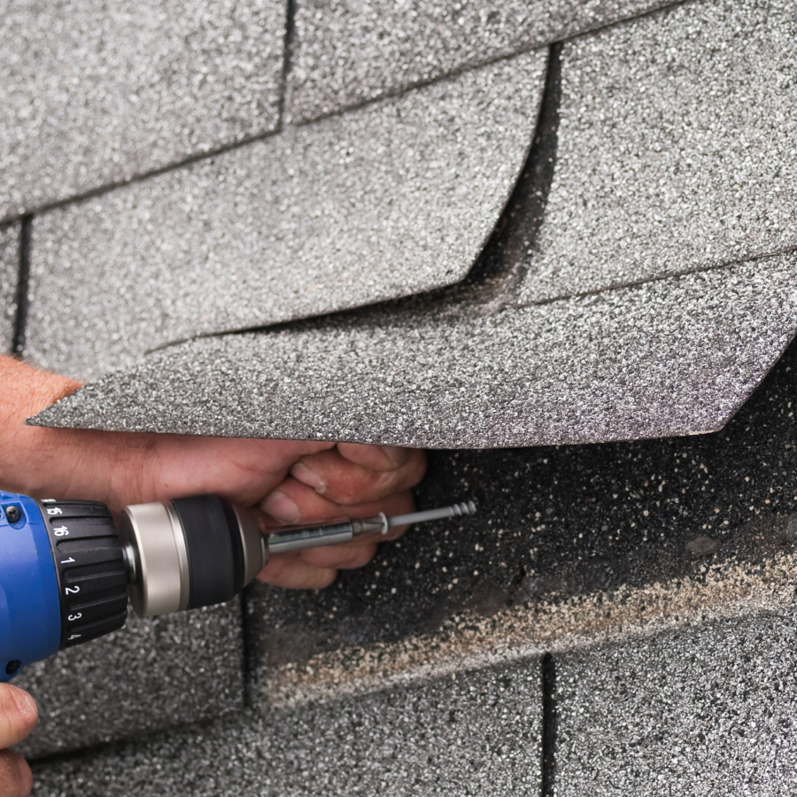 A person is fixing a roof with a drill