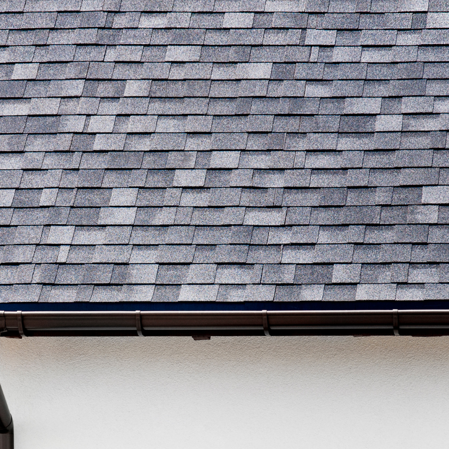 A close up of a roof with shingles and a gutter.