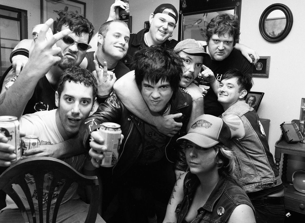 Group of people posing closely together indoors, smiling and making playful gestures in a black-and-white photo. Shot on medium format film by Madison Avery Somerville. Developed and printed in a traditional wet darkroom by the photographer.