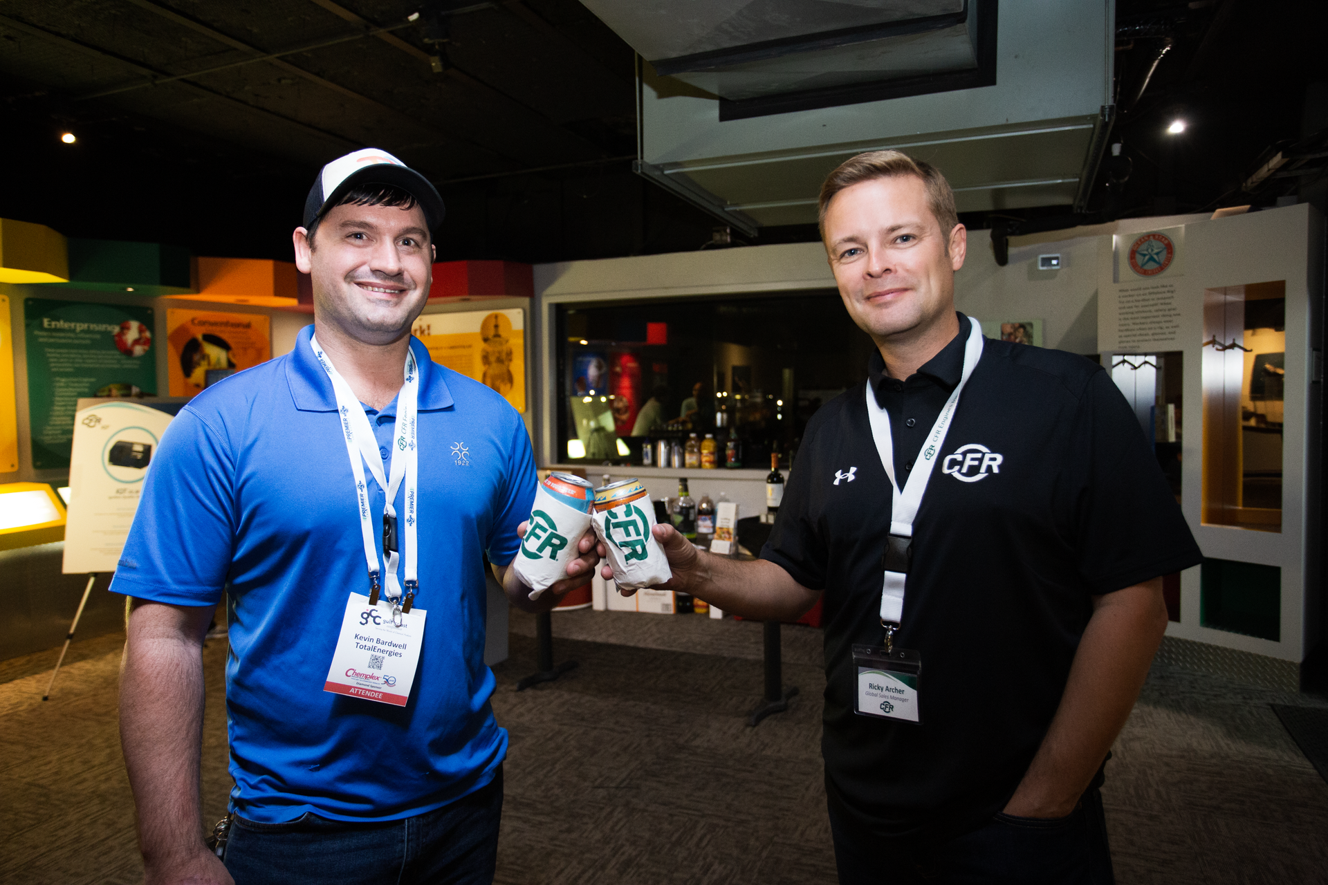 Two men are standing next to each other holding cups of coffee.