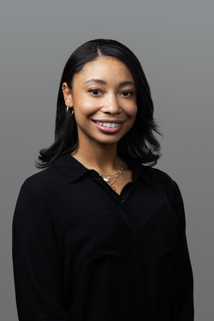 The woman is wearing a black blouse and smiling for the camera.