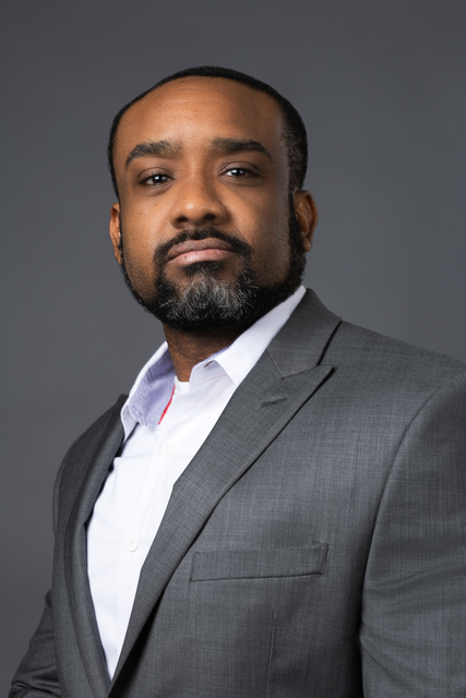 A man with a beard is wearing a suit and a white shirt.