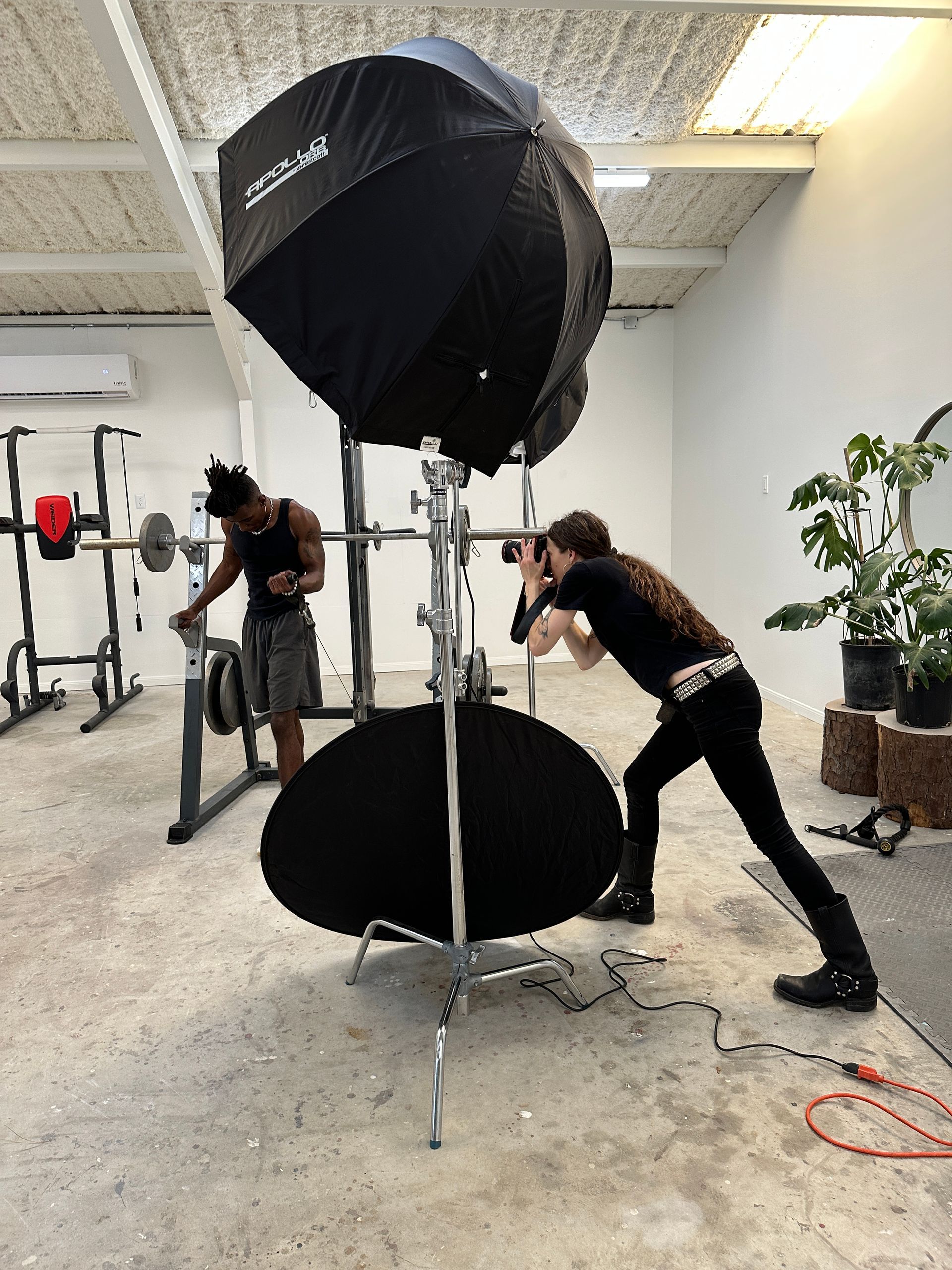 Two people adjusting a large studio light in a white photography studio