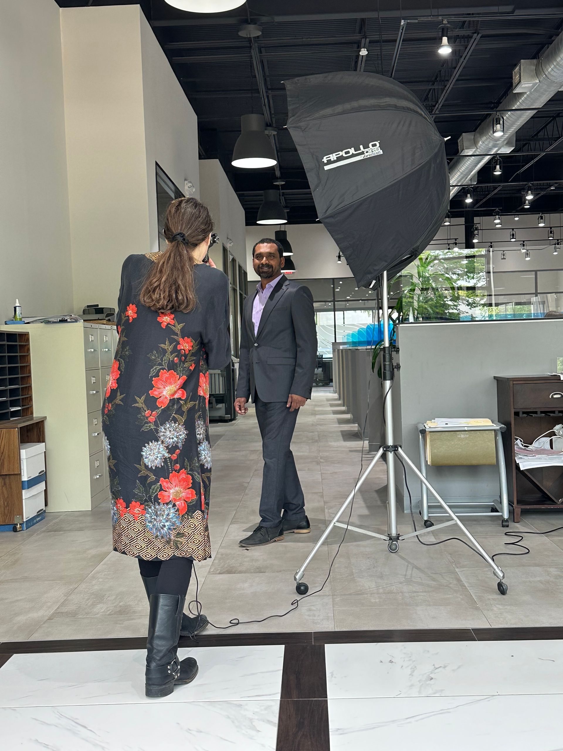 Two people talking in an indoor studio with a large softbox light and equipment cases.